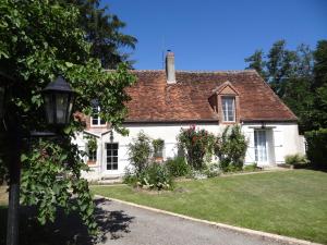 une maison blanche avec une cour verdoyante devant elle dans l'établissement Gîte des Bruyères, à Graçay