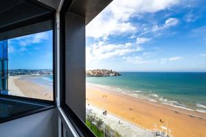 Blick auf den Strand aus dem Fenster eines Gebäudes in der Unterkunft Apartamento Ezcurdia 22 Playa de San Lorenzo primera línea in Gijón