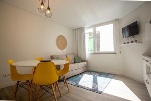 ein Wohnzimmer mit einem Tisch und gelben Stühlen in der Unterkunft Downtown PDL in Ponta Delgada
