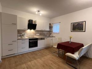 a kitchen with white cabinets and a table with chairs at Ferienwohnungen Blazej am Turnersee in Sankt Primus am Turnersee