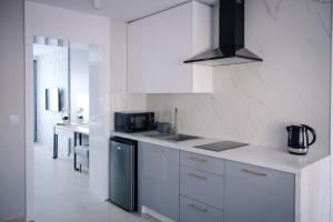 uma cozinha com armários brancos e um aparelho preto em Apartament Turysta em Licheń Stary