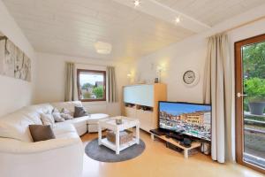 ein Wohnzimmer mit einem weißen Sofa und einem großen TV in der Unterkunft Seepark Kirchheim Ferienhaus bei Anne mit Sauna in Kirchheim