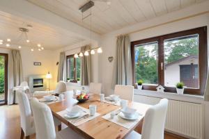 a dining room with a wooden table and white chairs at Seepark Kirchheim Ferienhaus bei Anne mit Sauna in Kirchheim