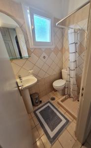 a bathroom with a sink and a toilet and a window at SPITI MAGDALINI in Agios Georgios Pagon +16 photos