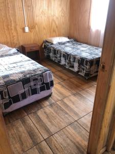 Habitación con 2 camas y suelo de madera. en Cabañas melinka en Licán Ray