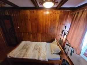 ein Schlafzimmer mit einem Bett in einer Holzwand in der Unterkunft RUSTIC Vidra in Vidra