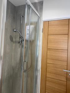 a shower in a bathroom next to a wooden door at WORTHING BEACH 180 - 2 bed seafront apartment with private parking in Worthing +56 photos