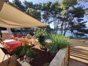 un patio con mesa, sillas y árboles en Stone Villa Hvar Ana and Nikola Beachfront en Jelsa
