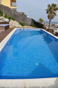uma grande piscina azul ao lado de uma casa em Villa Miramar Panoramic Views em Santa Susanna