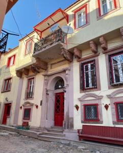 een gebouw met een rode deur en een balkon bij Cunda Bebekli Pansiyon in Ayvalık