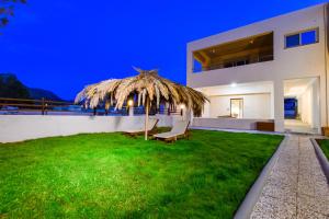 Una casa con un patio de césped con un banco y una sombrilla de paja. en Coastal Apartment 1, en Stavros 22 fotos más