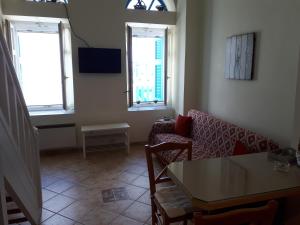 sala de estar con sofá, mesa y 2 ventanas en Roula's Suites, en Ándros