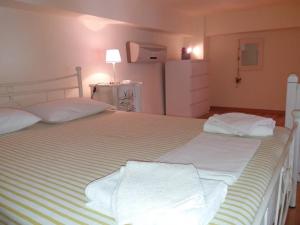 アンドロスにあるRoula's Suitesのベッドルーム1室(白いシーツが備わるベッド2台付)