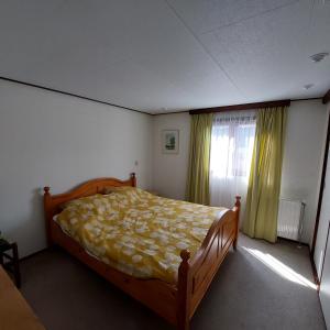 a bedroom with a bed and a window with green curtains at Vakantie op de Veluwe in Lunteren