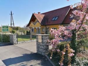 una casa amarilla con flores rosas delante en Ferienwohnung Pichler, en Leibnitz