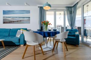 - un salon avec un canapé bleu, une table et des chaises dans l'établissement Apartament z basenem "Przy Morzu", à Rewal