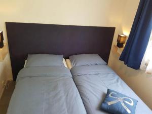 een paar bedden in een slaapkamer met blauwe gordijnen bij Inviting bungalow in Gelderland with garden in Garderen