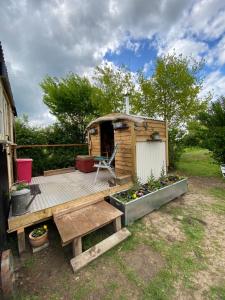 una terraza de madera con un banco y una casa en Mr Hares shepherd hut en Mellis