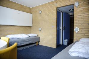 Cette chambre comprend 2 lits et un mur en briques. dans l'établissement Idrætscenter Jammerbugt, à Fjerritslev