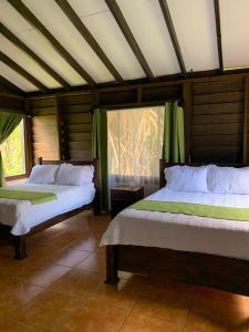 two beds in a room with green curtains at Colinas del Miravalles Hotel & Hot Springs in Hacienda Guayabo