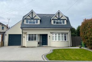 a white house with a garage and a driveway at Stunning 5 bed house in Surrey Minimum stay 5 nights in Sunbury