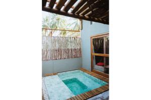 a swimming pool in a house with a window at Vila do Porto, Praia do Patacho - Bangalô Toque in Pôrto de Pedras