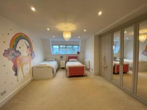 um quarto com 2 camas e um mural em arco-íris em Stunning 5 bed house in Surrey Minimum stay 5 nights em Sunbury