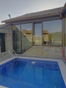 uma piscina em frente a uma casa com janelas em Casa rustica en Armenteira em Pontevedra
