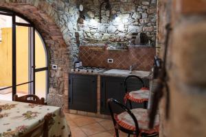 cocina con pared de piedra, mesa y sillas en Vico Tauro House, en Taormina