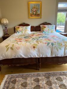 a bedroom with a bed with a floral bedspread at Under the Tree - Bed & Breakfast in Kelowna