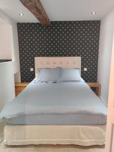 ein Schlafzimmer mit einem großen Bett mit gemusterter Wand in der Unterkunft Logement neuf centre du village aux pieds du château in Grimaud