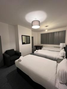 a hotel room with two beds and a chair at The Bake Apartment - 5 bedroom Large Apartment sleeps up to 16 person in Newcastle upon Tyne