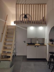 eine Küche mit weißen Schränken und eine Treppe in einem Zimmer in der Unterkunft Apartman Dux 2 in Karlovac