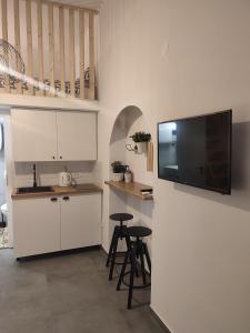 a kitchen with white cabinets and a flat screen tv on a wall at Apartman Dux 2 in Karlovac