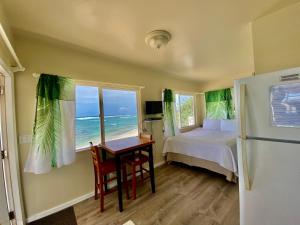 1 dormitorio con cama, escritorio y ventana en Mokulē'ia Beach Houses at Owen's Retreat, en Waialua