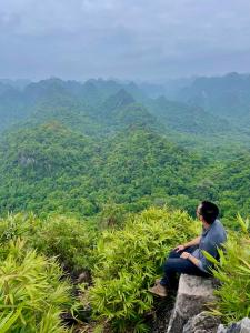 a man sitting on a rock looking at the mountains at Viet Hai Lan Homestay in Cat Ba
