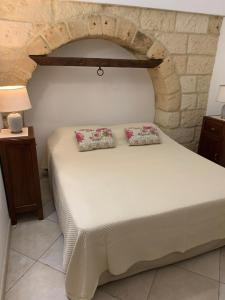 una camera da letto con un letto bianco con due cuscini sopra di Duomo Apartment a Nardò