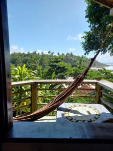 a hammock on a porch with a view of the ocean at Chalé na Praia da Tiririca in Itacaré