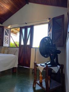a room with a fan on a table and a bed at Chalé na Praia da Tiririca in Itacaré