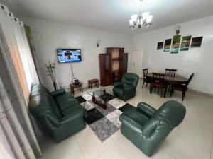 a living room with a green leather couch and a table at Résidence Allégra in Yaoundé