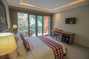 a bedroom with a bed and a balcony with a television at Aji Lodge Bungalow in Ubud