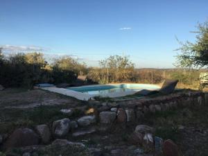 a swimming pool in a field with a stone wall at Rincon La Magda in Ciudad Lujan de Cuyo