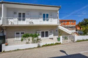 een wit huis met witte balkons in een straat bij Apartment Filomena in Primošten