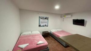 um pequeno quarto com duas camas e uma televisão em Alojamiento Mamá Juana em Ríohacha