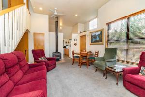 een woonkamer met een rode bank en stoelen en een tafel bij Arrow Getaway - Arrowtown Holiday Home in Arrowtown