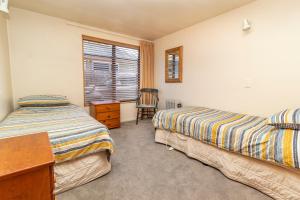 een slaapkamer met 2 bedden, een bureau en een stoel bij Arrow Getaway - Arrowtown Holiday Home in Arrowtown