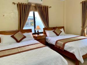 Phong Nha Orient Hotel في فونغ نها: غرفة نوم بسريرين ونافذة