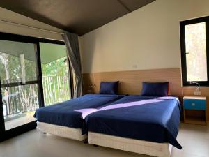 een slaapkamer met een bed met blauwe lakens en een raam bij Khu nghỉ dưỡng Làng An Bình in Yên Bình
