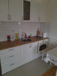 - une cuisine avec des placards blancs et un évier dans l'établissement Apartment Rustik, à Novi Sad