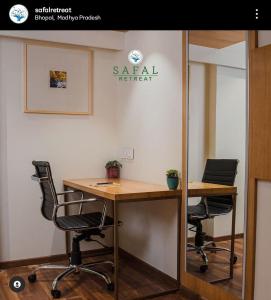 an office with two chairs and a desk and a mirror at Safal Retreat in Bhopal